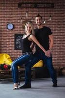 pareja joven bailando música latina bachata, merengue, salsa. pose de dos elegancia en el café con paredes de ladrillo foto