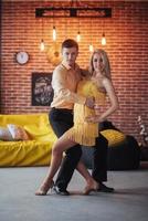 Young couple dancing latin music. Bachata, merengue, salsa. Two elegance pose on cafe with brick walls photo
