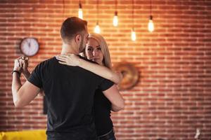 Young couple dancing latin music. Bachata, merengue, salsa. Two elegance pose on cafe with brick walls photo