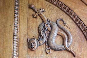 Devil snake symbol. Fantasy magic creature on an old door, 12th Century Abbey in Italy. photo