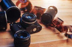 Old film camera and a roll of  on wood photo