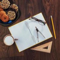 Top view of notebook, stationery, drawing tools and a few cups  coffee. photo