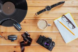 The old film camera and roll film and notebook with pencil on a wooden background photo