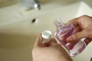 women hand hold a mouthwash liquid container photo