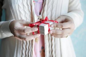 mano de mujer sosteniendo una pequeña caja de regalo en forma de corazón foto