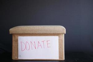 Donation box on table against black background photo