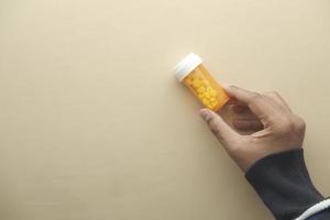 young man hand holding orange color pill container photo