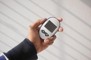 man's hand measuring blood sugar level photo