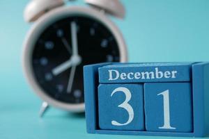 wooden calendar set on the 31 of December and clock on table photo