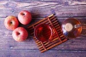 Vinagre de manzana en botella de vidrio con manzana verde fresca en la mesa foto