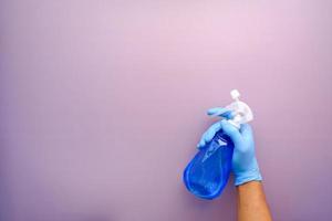 hand in blue rubber gloves holding spray bottle with copy space photo