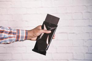 holding dark chocolate against a white wall photo