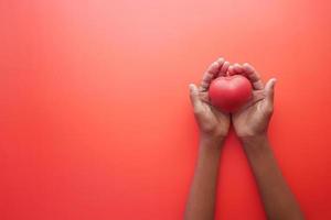 man hand in protective gloves holding red heart on blue photo