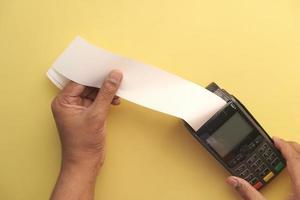 POS machine and long roll paper on yellow photo