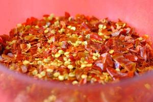 close up of red chili flakes in a bowl on red photo