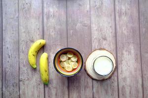 vaso de leche y plátano en la mesa por la mañana foto