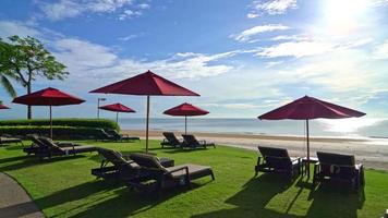 guarda-chuva vermelho e cadeira de praia com fundo de praia do mar e céu azul e luz do sol