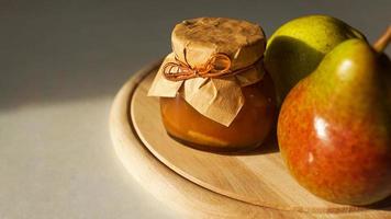 Delicious pear jam and fresh fruits on wooden cutting board. Homemade marmalade photo