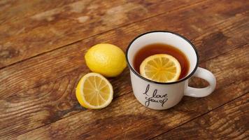 Cup of black tea and lemons on wooden table, top view. Prevention of colds photo