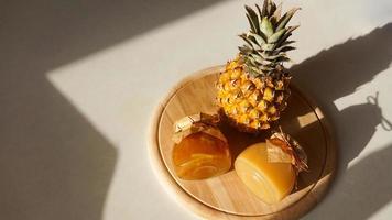 Pineapple jam in glass jar and fresh pineapple fruit with hard shadows photo
