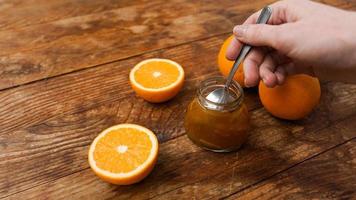 Jar of orange jam on white wooden background, top view. Woman hand with spoon photo