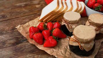 Slices of bread and delicious strawberry jam jar and fresh berries on wooden photo