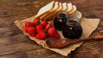 Slices of bread and delicious strawberry jam jar and fresh berries on wooden photo