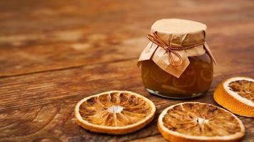 Jar of orange jam on wooden background from top view. Homemade marmalade photo