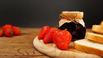 Slices of bread and delicious strawberry jam jar and fresh berries on wooden photo