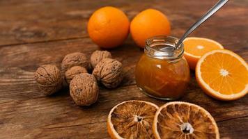 Sweet orange jam or marmalade dessert with walnuts on wooden background photo