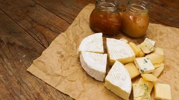 Cheese on craft paper with home made jam and honey in glass jar, food concept photo