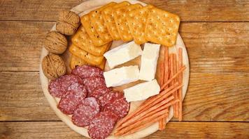 Meat and cheese plate for appetizers. Sausage, cheeses, crackers, nuts on wooden photo