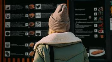 Woman at an urban street food court chooses food from a menu photo