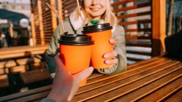 dos amigos tocan vasos de papel con vino caliente o té caliente en un soleado día de invierno foto