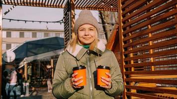 Woman carries two cups of coffee or mulled wine at the city outside food court photo