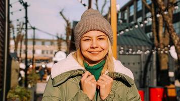 hermosa joven rubia mira con una sonrisa mientras está de pie al aire libre foto