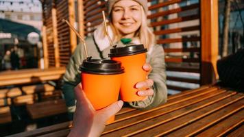 Two friends clink paper cups with mulled wine or hot tea on a sunny winter day photo