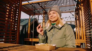Woman eating tasty french fries in outdoor cafe. Sunny winter day photo