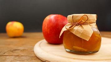 Apple jam in a transparent glass jar. Jam from apples on a wooden background photo