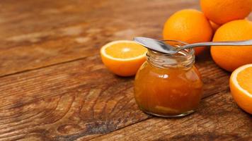 Jar of orange jam on wooden background from top view. Place for text. photo