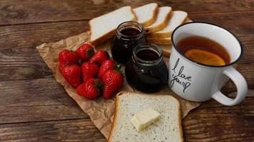 White cup of black tea with lemon. Sandwiches with strawberry and jam jar photo