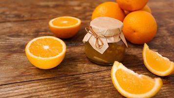 Jar of orange jam on wooden background from top view. Homemade marmalade photo