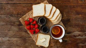 White cup of black tea with lemon. Sandwiches with strawberry and jam jar