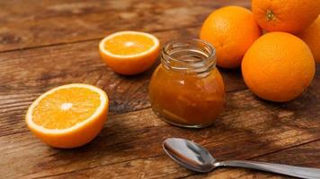 Jar of orange jam on wooden background from top view. Homemade marmalade