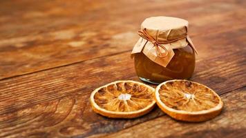 Jar of orange jam on wooden background from top view. Homemade marmalade photo