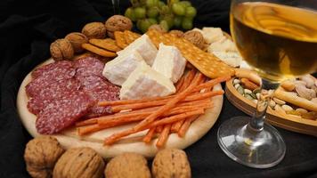 Cheese platter with assorted cheeses, grapes, nuts over black background