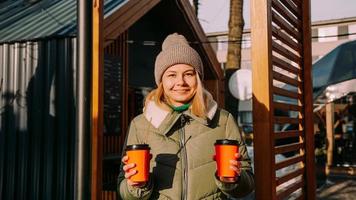 Woman carries two cups of coffee or mulled wine at the city outside food court photo