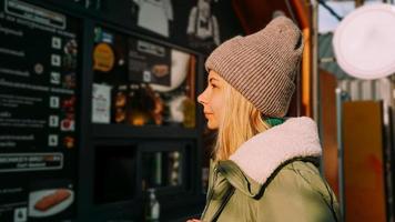 Woman at an urban street food court chooses food from a menu photo