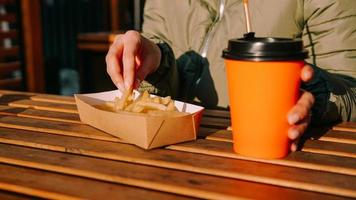 mujer comiendo papas fritas en un café al aire libre. centrarse en la mano con patata foto