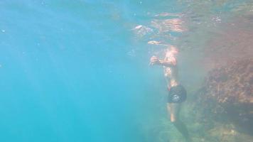 Man jumps and swimming under the water in pristine blue ocean water, amazing snorkeling adventure.